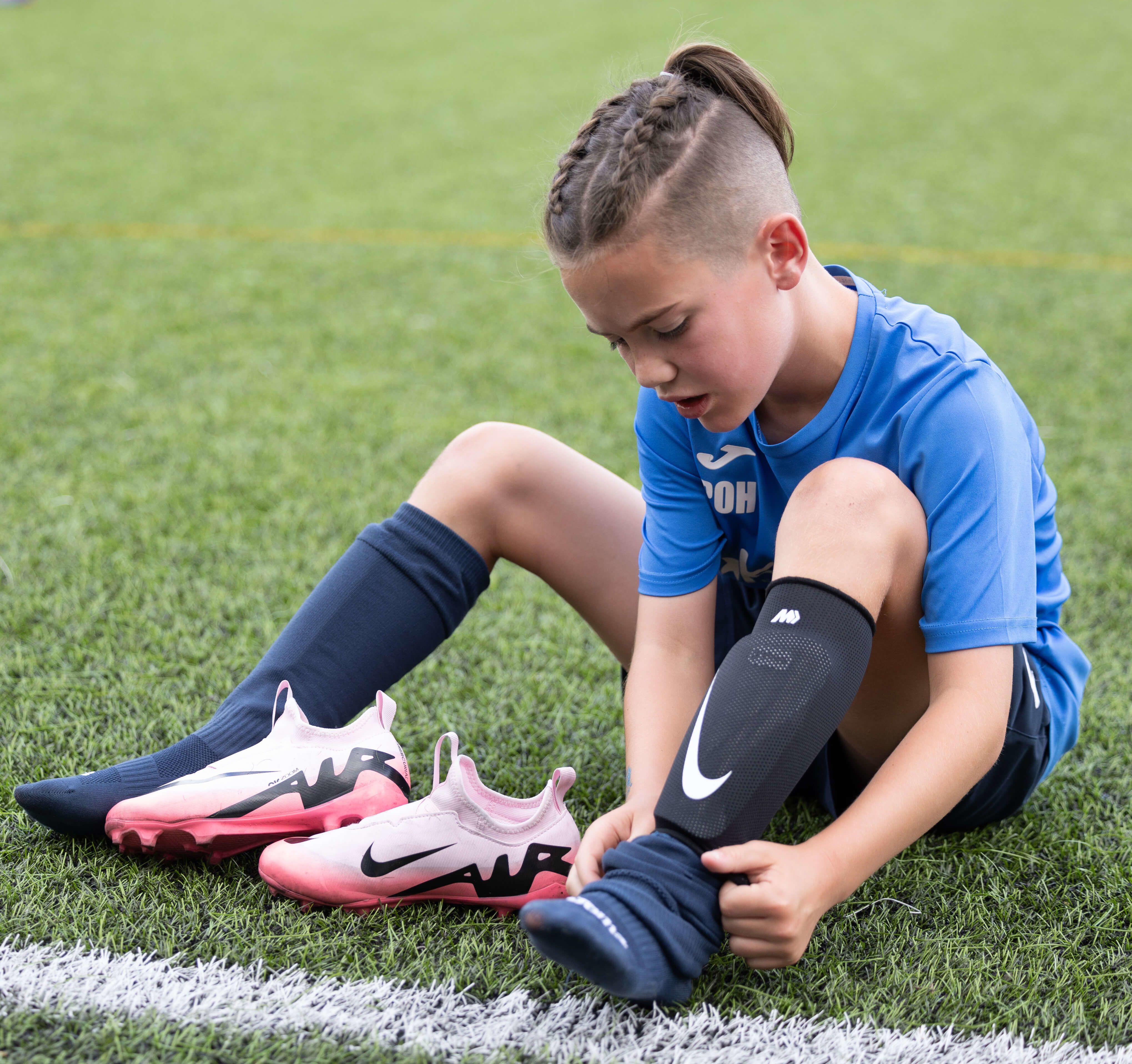 Child football player putting on shoes